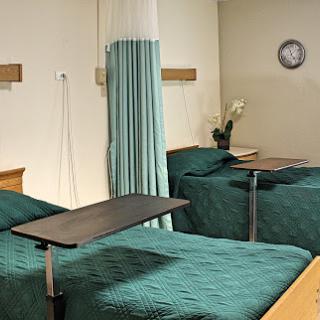 A view of a hospital patient room featuring two beds separated by a curtain.