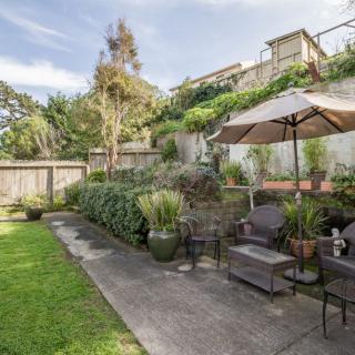 A beautifully landscaped backyard with a cozy patio area, featuring outdoor seating and an umbrella.