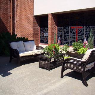 A cozy outdoor patio setup with wicker furniture and plants, basking in the sun.
