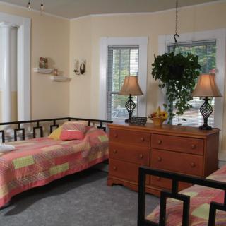 A cozy bedroom with twin beds, a dresser, and soft lighting from two lamps.