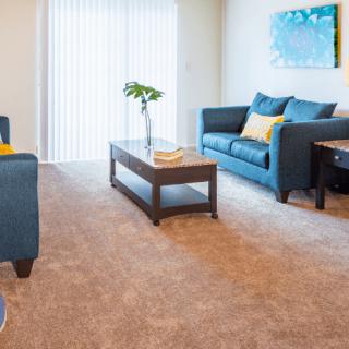 A modern living room with a blue sofa, wooden coffee table, and bright decor.