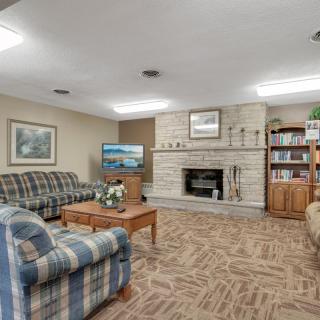A cozy living room featuring a fireplace, comfortable sofas, a television, and bookshelves.