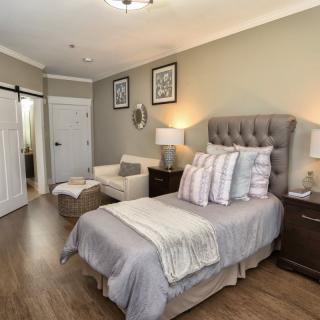 A cozy and modern bedroom with a neatly made bed, an armchair, and elegant decor.