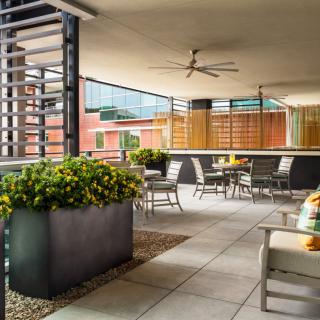 A modern outdoor patio with comfortable seating and lush plants in an urban setting.