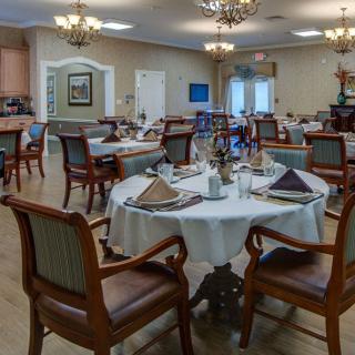 An elegantly furnished dining room with neatly arranged tables and chandeliers.