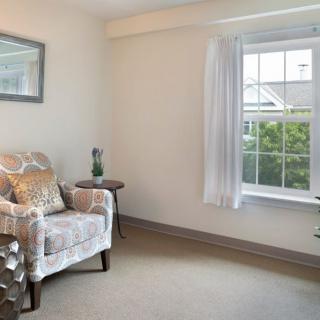 A cozy living room features a comfortable armchair and a large window allowing natural light.