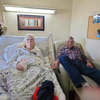 An elderly couple sharing a moment together in a hospital room.