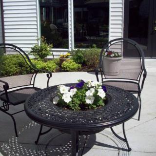 A patio set with a round table and two chairs, featuring a floral centerpiece.