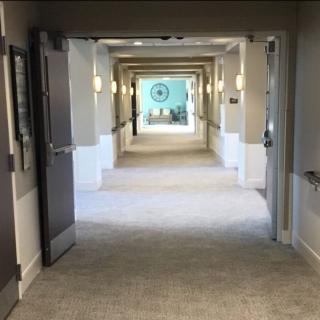 A long, lighted hallway with multiple doors and a bright end view.