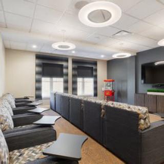 A modern lounge area with comfortable seating, ceiling lights, a flat-screen television, and a popcorn machine.