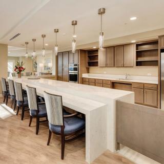A modern kitchen with a large island and seating area, featuring pendant lighting and wood flooring.