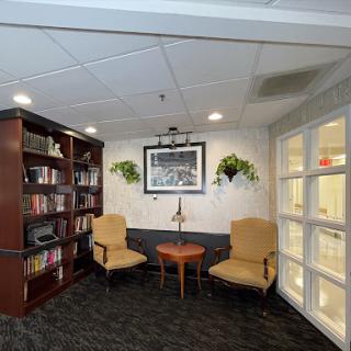 A cozy lounge area featuring comfortable chairs, a small table, and a bookshelf filled with books.
