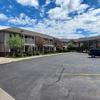A view of a residential apartment complex with a parking lot and a scenic cloudy sky.