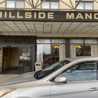 The exterior view of Hillside Manor, showcasing its welcoming entrance and parked vehicle.