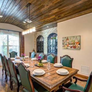 An elegant dining room with a wooden ceiling and traditional furniture, featuring a large table set for a meal.
