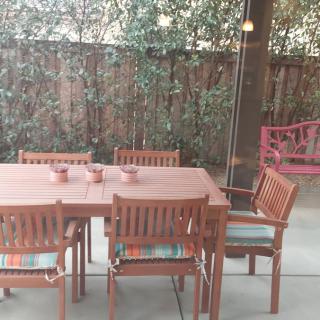 A cozy backyard patio setup with a wooden table, chairs, and a swing.