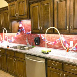 A modern kitchen featuring wooden cabinets, a sleek countertop, and stylish sinks with creative lighting.