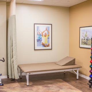 A well-equipped therapy room featuring a treatment table, exercise tools, and decorative artwork.
