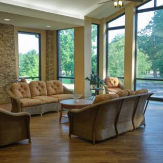A cozy living room with large windows, a wooden floor, and comfortable seating.
