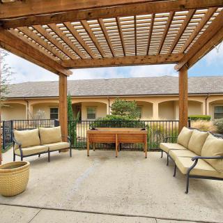 A cozy outdoor patio with a wooden pergola and cushioned seating.