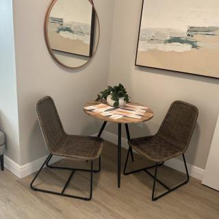 A cozy dining nook with a small round table and two chairs, complemented by wall art and a mirror.