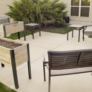 A cozy outdoor patio area with tables, chairs, and planter boxes.
