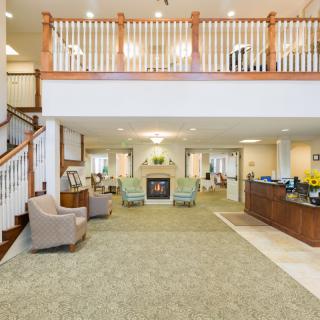 A spacious and well-decorated lobby with a reception desk, staircase, and seating area.