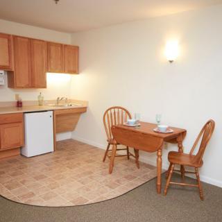 A compact apartment kitchen with a small dining table and chairs.