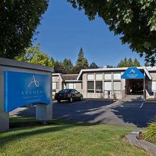 A building with a blue awning and signage, surrounded by trees and a parking lot.