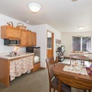 A cozy kitchen and dining area with wooden cabinets and a set table.