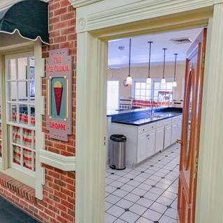 Interior view of an ice cream parlor kitchen with a counter and tiled floor.