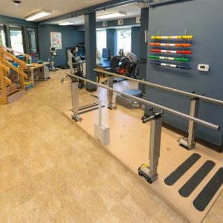 A physical therapy clinic featuring parallel bars and rehabilitation equipment.