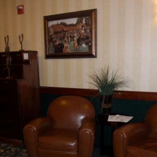 A cozy waiting area with leather chairs, a framed painting on the wall, and a small plant decorating the space.