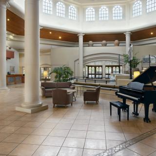 A spacious lobby with a grand piano and elegant columns.