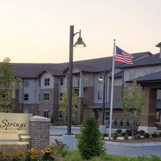 A residential complex with well-maintained landscaping and an American flag in front.