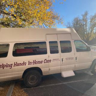 A van for in-home care services parked under autumn foliage.