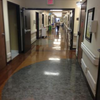 A view down a hospital corridor with doors and medical equipment along the sides.