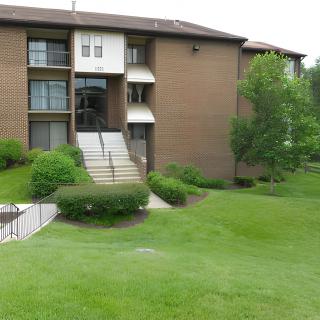 A view of a residential apartment building surrounded by well-maintained grass and trees.