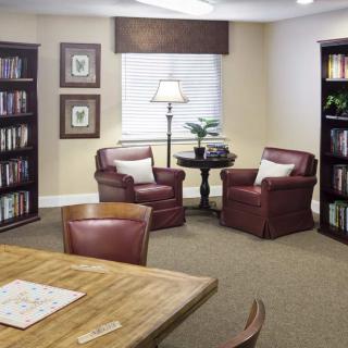 A cozy reading room with bookshelves, comfortable chairs, and a wooden table.