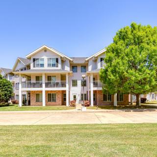 A large residential house with multiple stories and a spacious lawn under a clear blue sky.