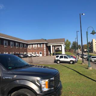 A view of a building with several vehicles parked in front, including law enforcement cars, under a clear blue sky.