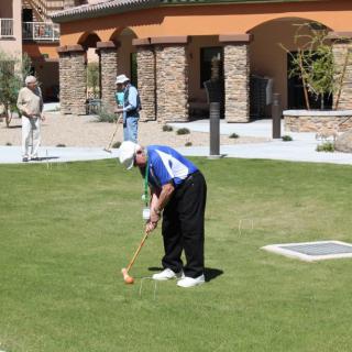 A person preparing to putt on a golf course with buildings in the background.