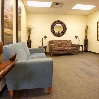 A waiting room with sofas, a mirror, and decorative elements.
