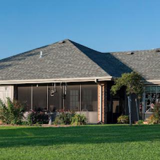 A cozy home with a spacious lawn and a screened porch.