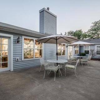 A spacious patio area with tables, chairs, and a large umbrella next to a house.