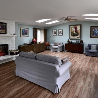 A cozy living room with wood flooring, featuring a sofa, armchairs, a fireplace, and artwork on the walls.