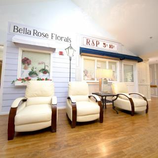 Comfortable waiting area with white chairs and a flower shop backdrop.