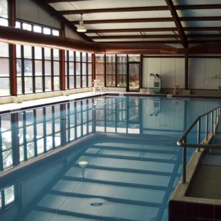 An indoor swimming pool with large windows and clean, calm water.