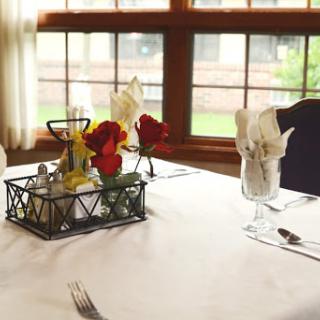 An elegantly set dining table featuring flowers and neatly arranged napkins, illuminated by natural light.