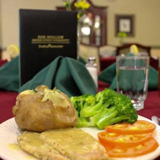A delicious meal featuring chicken, broccoli, baked potato, and sliced tomatoes served in a restaurant setting.